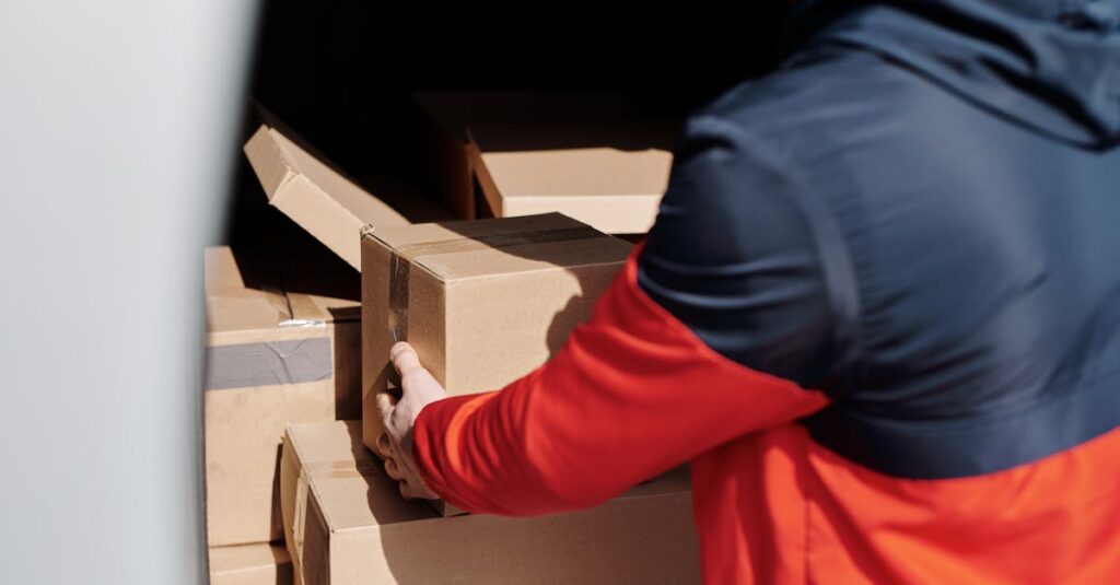 A delivery worker efficiently loads cardboard boxes into a vehicle for shipment.